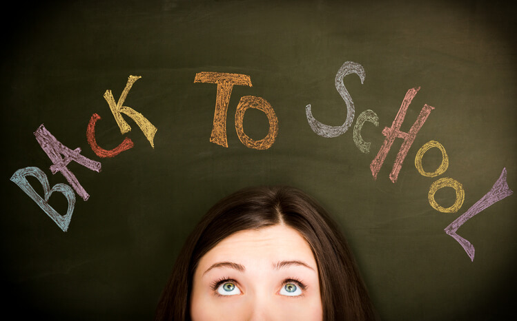 Young woman in front of "Back to school" concept on blackboard.